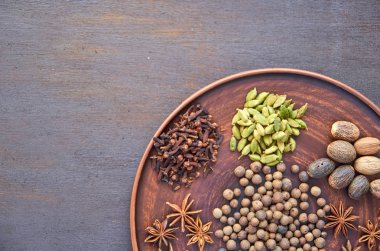 Aromatik baharatlar karanlık bir tabakta - yıldız anason, güzel kokulu biber, Hint kamışı kök, tarçın, Hindistan cevizi kahverengi zemin üzerinde kopya alanı sol tarafında ile. Baharat arka plan doku