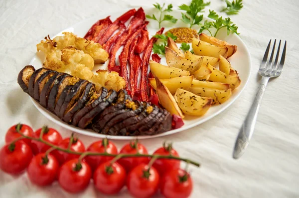 炸土豆、 茄子、 甜椒和花椰菜在白板上的装饰着叉子和新鲜的樱桃番茄 免版税图库图片