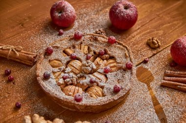 Elmalı turta taze kızılcık ve ceviz ile elma, zencefil ve tarçın ile dekore edilmiştir. Toz elmalı turta ahşap kahverengi zemin üzerinde yemeye hazır. Yan görünüm