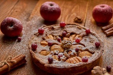 Toz elmalı turta taze kızılcık ve ceviz ile elma ve tarçın ile dekore edilmiştir. Toz elmalı turta ahşap kahverengi zemin üzerinde yemeye hazır. Yan görünüm