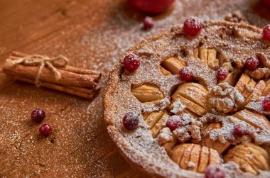 Elmalı turta taze kızılcık ve ceviz ile tarçın ile dekore edilmiştir. Sadece toz elmalı turta ahşap kahverengi zemin üzerine pişmiş. Yan görünüm