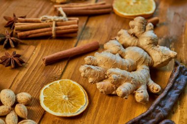 Zencefil ahşap kahverengi zemin üzerinde büyük bir parçası. Mulled şarap için malzemeler: kurutulmuş meyve, portakal, zencefil, tarçın, anason yıldız ve fındık. Görünümü kapatın