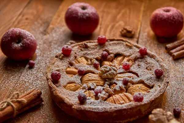 Toz elmalı turta taze kızılcık ve ceviz ile elma ve tarçın ile dekore edilmiştir. Toz elmalı turta ahşap kahverengi zemin üzerinde yemeye hazır. Yan görünüm