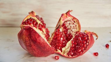 Büyük kırmızı nar tohumları üzerinde beyaz beton bckground açıldı. Taze nar hafif ahşap arka plan üzerine dilimlenmiş. Görünümü kapatın