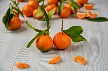 Yeşil yaprakları ile iki taze mandalina. Soyulmuş mandalina portakal ve mandalina portakal dilimleri gri ahşap tahta üzerinde. Narenciye arka plan. Yan görünüm