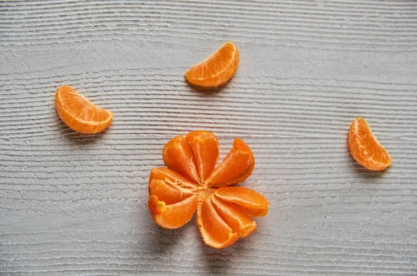 Three tangerine orange slices on the gray wooden board with free copy space. Fresh raw mandarin orange and peeled yellow tangerine. Top view