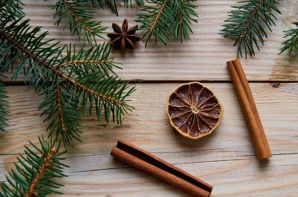 Narenciye ile tarçın, anason star Noel ağacı dalları ile dekore edilmiş ahşap arka plan üzerinde kurumuş. Geleneksel baharat mulled şarap, Noel ekmek için. Yeni yıl kompozisyon tebrik kartı.