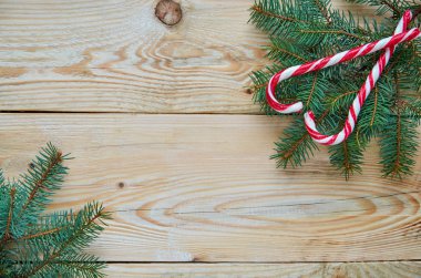 Noel ağacı dalları üzerinde sağ üst köşedeki üzerinde iki kırmızı şeker külah kalbinde. Ücretsiz kopya alanı ile kahverengi ahşap arka plan dallarda köknar ile yeni yıl ya da Sevgililer günü tatlılar süslemeleri