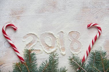 Mutlu yeni yıl 2018 yılında un ahşap masa üzerinde kırmızı şeker ve Noel ile dekore edilmiş üç şube imzala. Üstten Görünüm. Kopya alanı