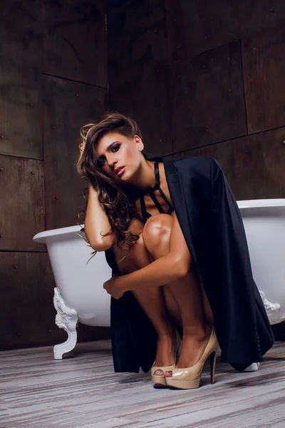 Mooi meisje zit op de badkuip in jas — Stockfoto