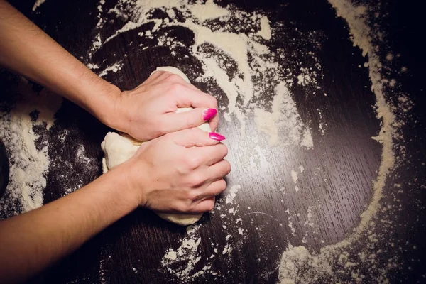 Een meisje bereidt deeg voor pizza op een zwarte achtergrond — Stockfoto