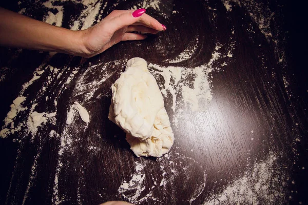 A girl prepares dough for pizza on a black background — Stock Photo, Image