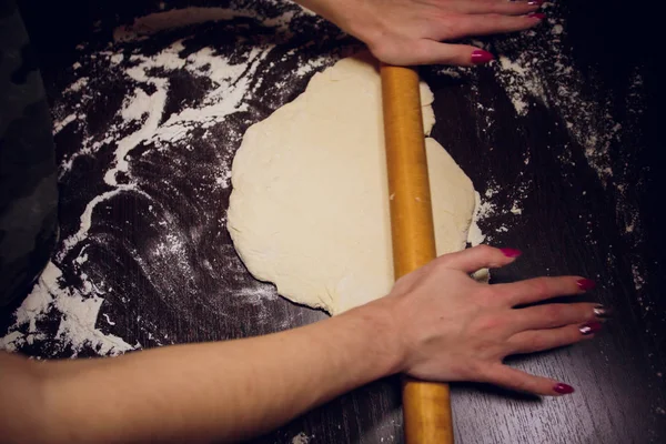Девушка готовит тесто для пиццы на черном фоне — стоковое фото