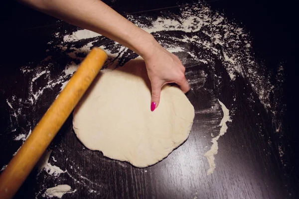 Ένα κορίτσι προετοιμάζει ζύμη για πίτσα σε μαύρο φόντο — Φωτογραφία Αρχείου