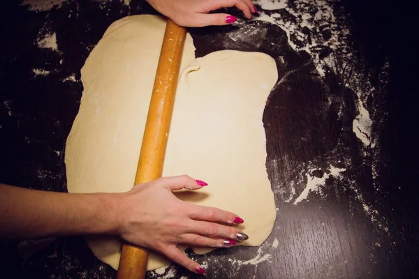Девушка готовит тесто для пиццы на черном фоне — стоковое фото