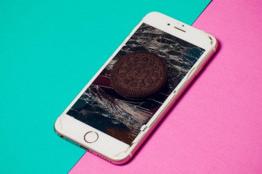 Yığılmış kırık ekran çikolatalı kurabiye ile modern hareket eden smartphone süt kavramı, modern bir mobil işletim sistemi hizmet.
