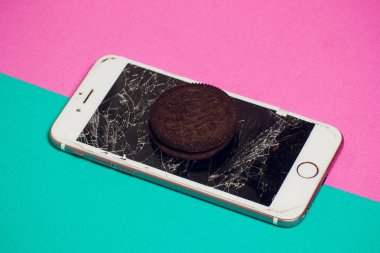Yığılmış kırık ekran çikolatalı kurabiye ile modern hareket eden smartphone süt kavramı, modern bir mobil işletim sistemi hizmet.
