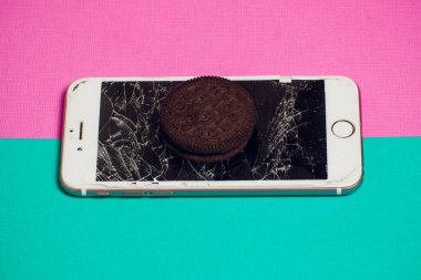 Yığılmış kırık ekran çikolatalı kurabiye ile modern hareket eden smartphone süt kavramı, modern bir mobil işletim sistemi hizmet.