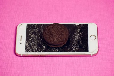 Yığılmış kırık ekran çikolatalı kurabiye ile modern hareket eden smartphone süt kavramı, modern bir mobil işletim sistemi hizmet.