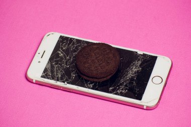 Yığılmış kırık ekran çikolatalı kurabiye ile modern hareket eden smartphone süt kavramı, modern bir mobil işletim sistemi hizmet.