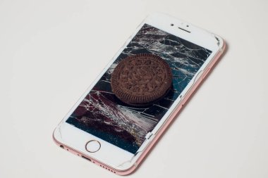 Yığılmış kırık ekran çikolatalı kurabiye ile modern hareket eden smartphone süt kavramı, modern bir mobil işletim sistemi hizmet.
