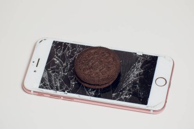 Yığılmış kırık ekran çikolatalı kurabiye ile modern hareket eden smartphone süt kavramı, modern bir mobil işletim sistemi hizmet.