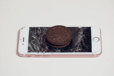 Yığılmış kırık ekran çikolatalı kurabiye ile modern hareket eden smartphone süt kavramı, modern bir mobil işletim sistemi hizmet.