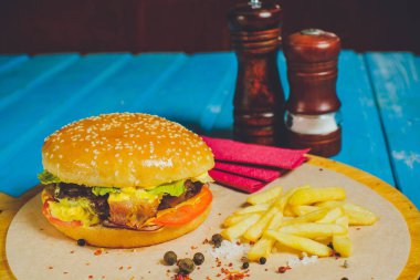 Taze et burger peynir, sebze ve kağıt, mavi ahşap arka plan üzerinde baharatlı domates sosu