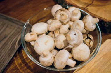 Ahşap arka plan üzerinde kahverengi kase taze beyaz mantar champignon. Üstten Görünüm. Kopya alanı.