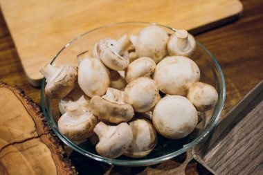 Ahşap arka plan üzerinde kahverengi kase taze beyaz mantar champignon. Üstten Görünüm. Kopya alanı.