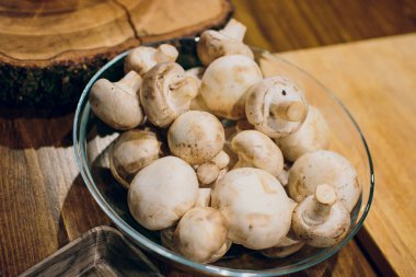 Ahşap arka plan üzerinde kahverengi kase taze beyaz mantar champignon. Üstten Görünüm. Kopya alanı.