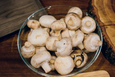 Ahşap arka plan üzerinde kahverengi kase taze beyaz mantar champignon. Üstten Görünüm. Kopya alanı.