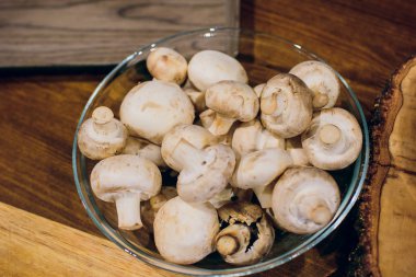 Ahşap arka plan üzerinde kahverengi kase taze beyaz mantar champignon. Üstten Görünüm. Kopya alanı.