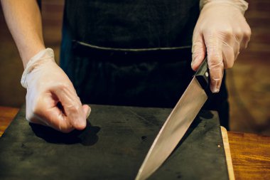 Erkek şef bıçağı ellerimle. Şef elinde bıçakla boş kesme tahtası üzerinde görüntü kırpılmış. Yemek hazırlamak olacak yemek.