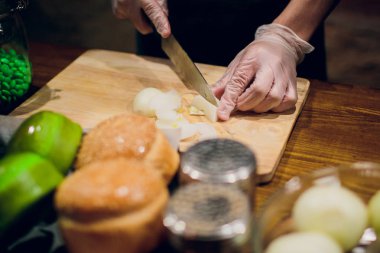 Ahşap tahtanın soğanını bıçakla kesen şefin elleri. Yemek hazırlığı. Sağlıklı beslenme ve yaşam tarzı.