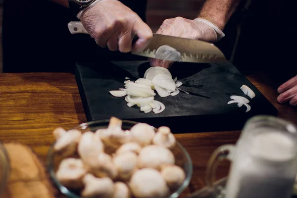 Руки шеф-повара с ножом режут лук на деревянной доске. Подготовка к приготовлению пищи. Здоровое питание и образ жизни . — стоковое фото