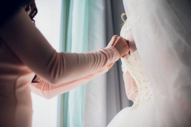 Nedime gelinliğin arkasında yay düğümü yapıyor.