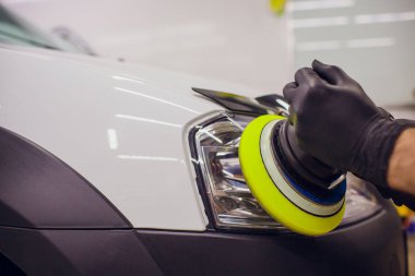 otomatik mekanik cilalama ve araba Far araba - oto tamircisi yörünge Parlatıcı ile adam detaylandırma parlatma. Seçici odak.