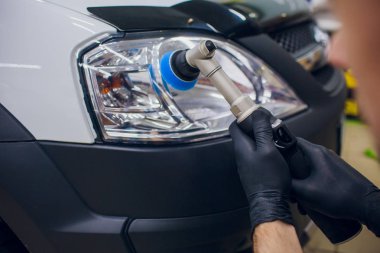 auto mechanic buffing and polishing car headlight Car detailing - man with orbital polisher in auto repair shop. Selective focus. clipart