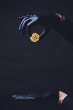 Bitcoin. El altın sikke bırakır. Siyah eldiven elinde. Kavram sonbahar Kripto para birimi. Siyah arka plan üzerine izole.