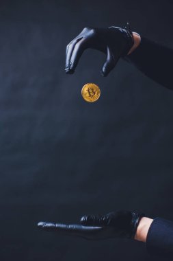 Bitcoin. El altın sikke bırakır. Siyah eldiven elinde. Kavram sonbahar Kripto para birimi. Siyah arka plan üzerine izole.