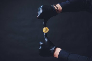 Bitcoins koluna yerleştirilen siyah eldiven elinde simge göster. Siyah arka plan üzerine izole