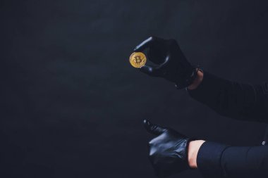 Bitcoins koluna yerleştirilen siyah eldiven elinde simge göster. Siyah arka plan üzerine izole