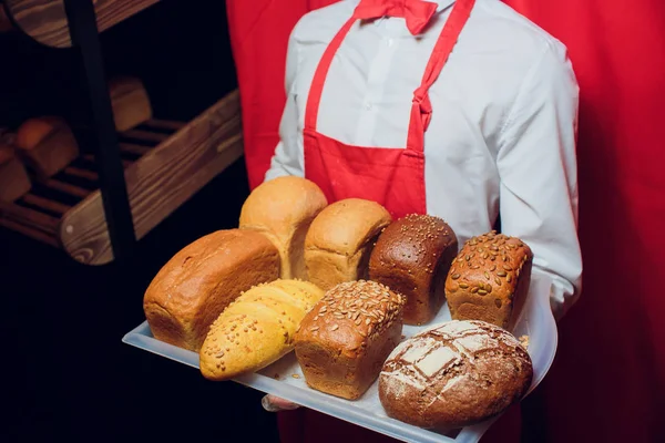 Baker guarda una bandeja con pan fresco . — Foto de Stock