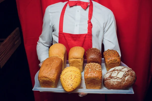Baker guarda una bandeja con pan fresco . — Foto de Stock