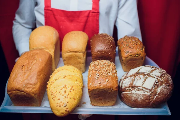 Baker guarda una bandeja con pan fresco . — Foto de Stock