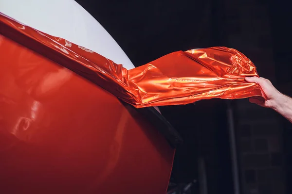 Auto wrapping specialist aanbrengen van vinyl folie of film op auto. beschermfolie met zaklamp te snijden. jacht, boot, schip, auto, stacaravan te verpakken. Oranje film — Stockfoto