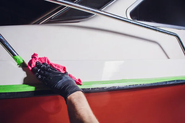 El hombre lava el yate de cubierta con trapo rosa. preparación en el pulido, yate de reparación, barco — Foto de Stock