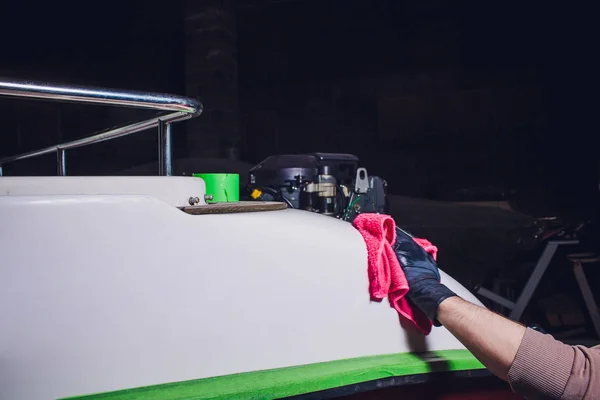 Мужчина моет палубу яхтой с розовой тряпкой. подготовка к шлифовке, ремонту яхты, лодки — стоковое фото