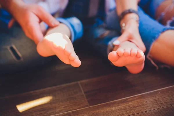 Adultos padres manos sosteniendo pequeños pies de bebé — Foto de Stock